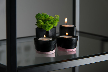 黑色和粉色混凝土烛台中的蜡烛和苔藓