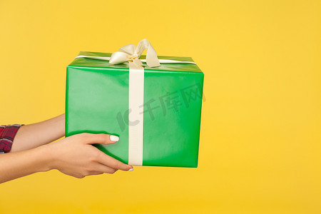 女手拿着礼盒的特写，手臂提供大绿色包装的礼物
