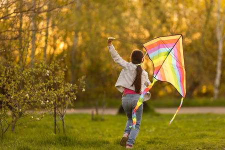 五颜六色的风筝摄影照片_快乐的孩子在户外玩五颜六色的风筝。