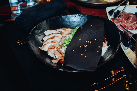 碗装蔬菜摄影照片_凯撒沙拉装在时尚的黑色碗里。