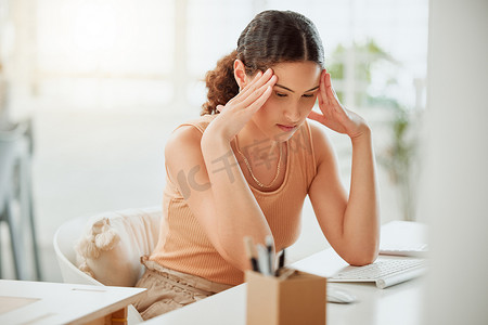 西班牙女摄影照片_一位焦虑的年轻西班牙裔女商人在办公室的电脑上工作时感到头痛。