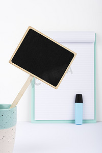 学习小黑板摄影照片_有重要消息的小黑板在书桌上的杯子与剪贴板和标记。