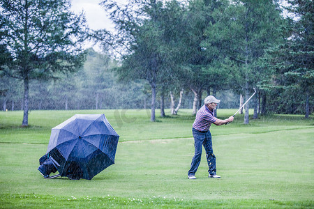 雨天的高尔夫球手在球道上挥杆