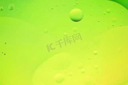 用油、水和肥皂制成的绿色和黄色抽象背景图片