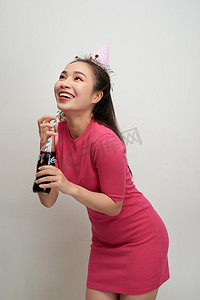 喝可乐的女孩摄影照片_美丽的疯狂微笑女人的肖像，她用吸管从瓶子里喝白色的苏打水