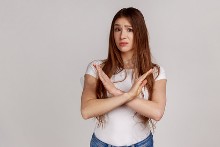 打叉手势摄影照片_失望的女孩交叉双手,做出停止否认的手势,明确表示
