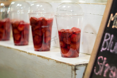 货架上塑料玻璃中的草莓和糖浆准备按客户订单制成冰沙