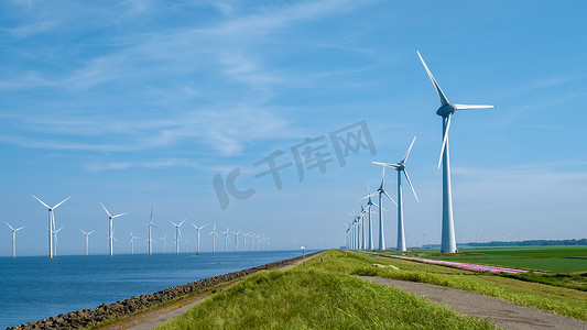 绿色的风车摄影照片_巨大的风车涡轮机、Westermeerwind 海洋公园的海上风车农场、荷兰弗莱福兰 Noordoostpolder 美丽明亮的日子里孤立在海上的风车