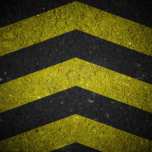 沥青纹理摄影照片_沥青纹理上的黄色和黑色警告标志