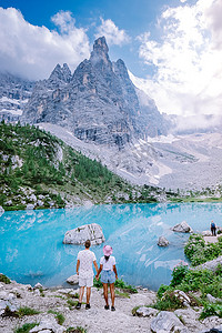 情侣参观意大利多洛米蒂山的蓝绿色湖，美丽的索拉皮斯湖 Lago di Sorapis 位于多洛米蒂山，意大利热门旅游目的地