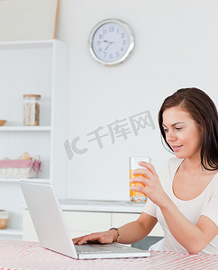 一位女士使用笔记本电脑喝果汁的肖像