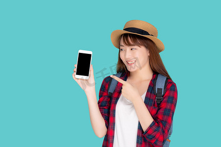 美丽的年轻亚洲女性展示智能手机，在蓝色背景的假期中展示和指向夏季旅行中的某些东西，亚洲女孩拿着智能手机。