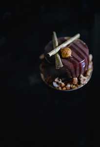 黑镜面背景摄影照片_豪华巧克力蛋糕蛋糕装饰着深色背景上焦糖爆米花的金色装饰。