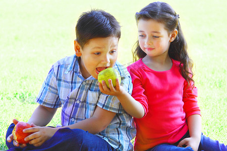 苹果游戏摄影照片_男孩和女孩坐在草地上玩耍