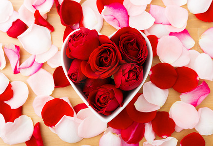 粉色心形花瓣摄影照片_心形碗内红玫瑰，旁边有花瓣