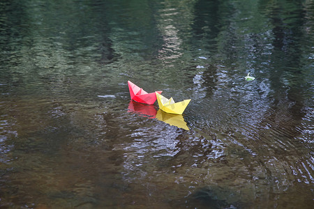 两艘五彩的纸船漂浮在溪流上