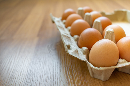 农业鸡摄影照片_特写红皮蛋放在一个纸板箱里，来自一家超市的木地板上。
