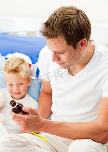 有魅力的父亲给生病的儿子喂止咳糖浆