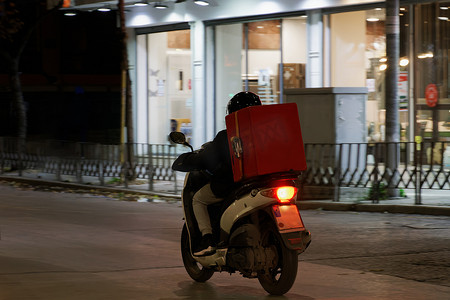 夜间，骑着无品牌摩托车在城市道路上超速行驶的快递员。