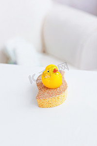 可爱鸭摄影照片_客厅海绵上一只黄色塑料鸭的特写