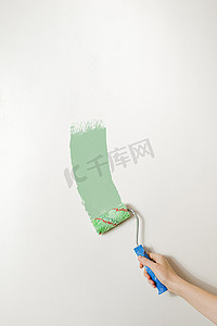 明亮的居家摄影照片_手拿着画笔靠在白墙上。