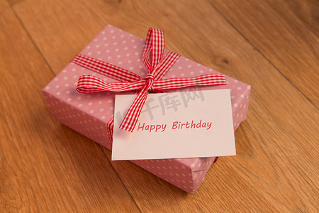 冰淇淋蛋糕当礼物摄影照片_粉色包装礼物，附有生日贺卡问候语