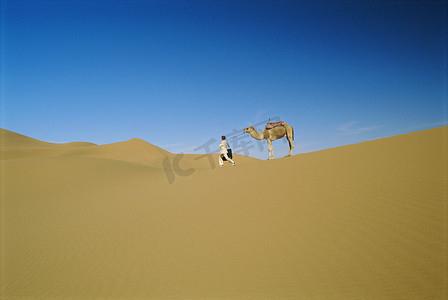 户外带着骆驼在沙漠中行走的女人（远处）