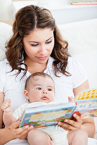 细心的妈妈给坐在家里的可爱宝宝读书