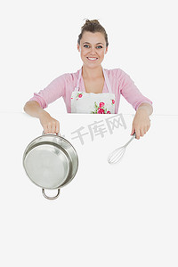 搅拌碗摄影照片_广告牌后面有钢丝搅拌器和搅拌碗的女人
