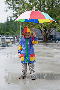 撑着伞站在雨下的男孩