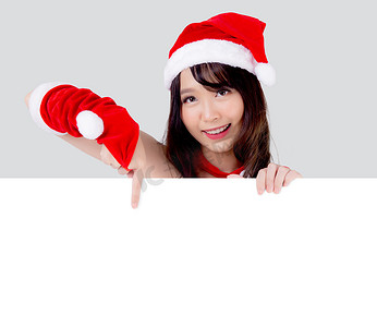 美丽的年轻亚洲圣诞老人妇女拿着白色背景的圣诞节空白板，亚洲女孩展示空横幅纸海报，并指出圣诞假期和新年广告。