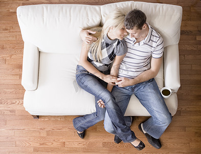 奶油色沙发摄影照片_年轻夫妇坐在爱情座椅上