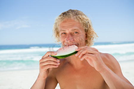 年轻人在海边吃一块西瓜