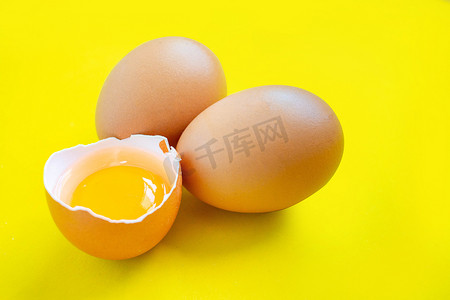 特写镜头破裂的棕色鸡蛋从超市购买放置在黄色背景上。