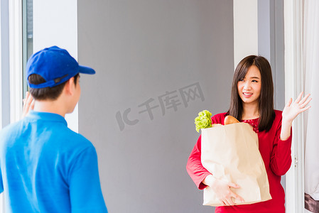 女顾客摄影照片_送货员提供杂货服务，将纸袋中的新鲜蔬菜送给女顾客