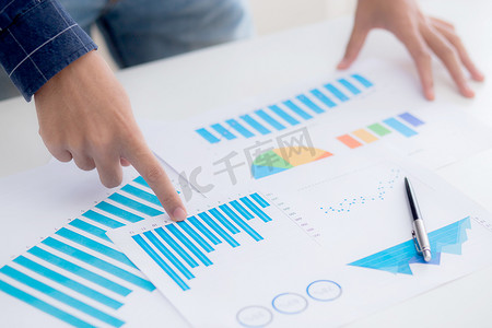 年轻商人的手指向文档数据图表和图表纸、营销和投资、金融、经济和金融增长、管理和规划的统计利润报告。