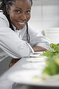 一位微笑的女厨师在厨房准备沙拉的特写肖像