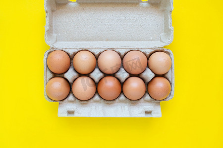 农业鸡摄影照片_在黄色背景的一家超市的纸板箱中特写红皮蛋。