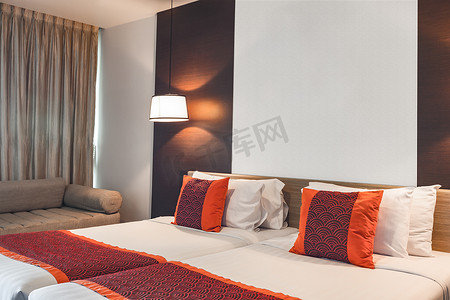 红色毛毯和枕头摄影照片_双人卧室的红色枕头配有白色床单和灯光