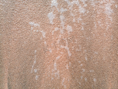 蓝色海浪纹理摄影照片_莫尔波在沿海沙子上，海浪的背景纹理和沙子上的泡沫。