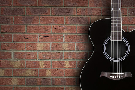 砖背景上的黑色原声吉他，带复制空间