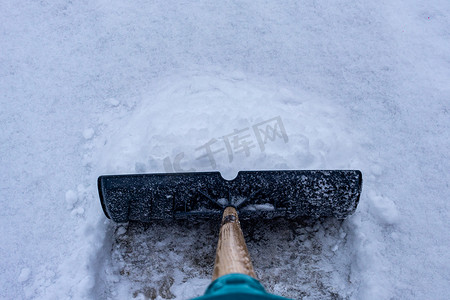 铲雪摄影照片_在冬季车道上铲雪