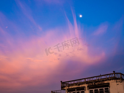 月亮和云朵摄影照片_粉红色的云朵和月亮在日落的天空中