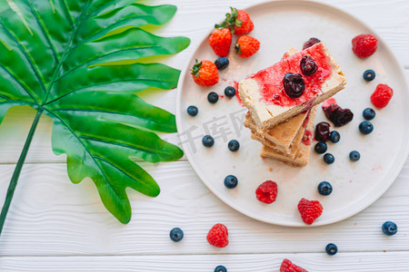 一片经典芝士蛋糕，白盘上有新鲜浆果 — 健康有机夏季甜点。