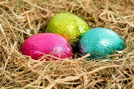 三个色彩缤纷的复活节彩蛋坐落在稻草巢中