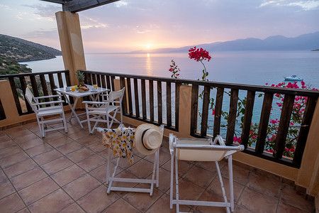 白色桌椅摄影照片_希腊地中海地中海日出时的桌椅和早餐