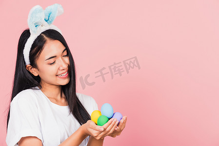 戴着兔耳微笑的女人手上拿着彩色复活节彩蛋礼物