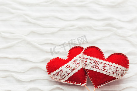 白色织物背景与皱褶。两颗带鞋带的心，爱的象征。