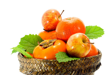 纸莎草摄影照片_纸莎草篮里的橙子、苹果和柿子。