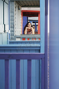 紧握扶手摄影照片_美丽的年轻女子靠在海滨别墅的栏杆上，望向别处